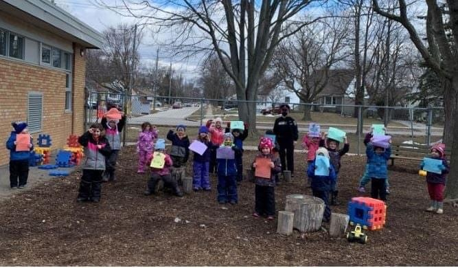 Students in the FDK class at St. Ursula Catholic School in Chatham present their artwork to a member of the Chatham-Kent Police Service