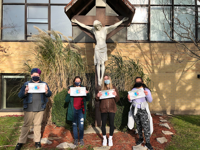 Students standing in front of crucified Jesus statue